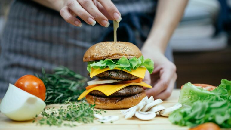 Woman preparing a handmade burger with cheese and lettuce